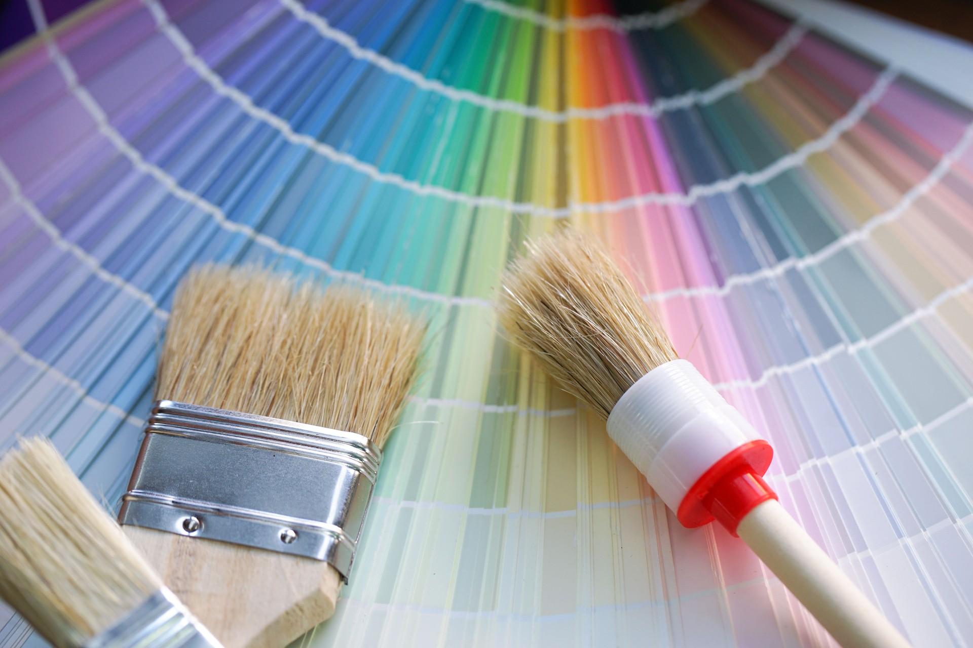 Painter and decorator work table with house project, color swatches, painting roller and paint brushes